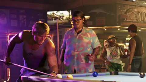 Holding a can at a bar while Jason lines up a shot at the pool table.