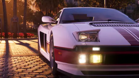 Pop-up headlights raised and fog lamps lit on a cobbled drive at sunset.