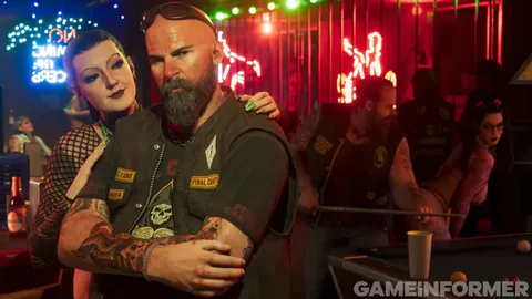 A bearded biker and a woman leaning on his shoulder in a neon-lit bar, a pool table behind them.