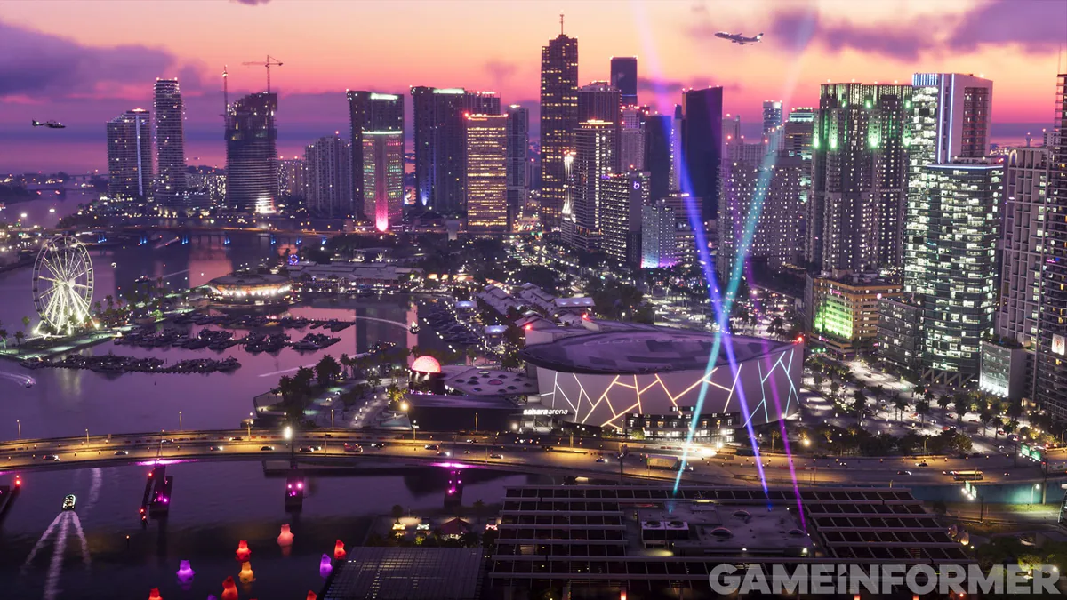 Vice City at night from above: the downtown towers, the bay, a lit arena and searchlights sweeping the sky.
