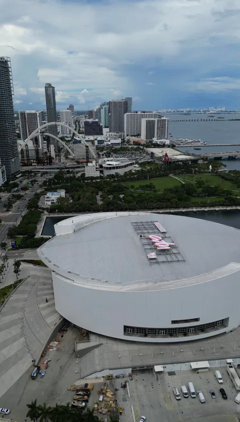 The round white arena from above, the lettering on its roof, the downtown skyline and the bay behind it.