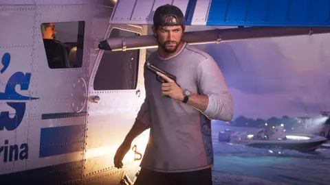 Pistol drawn beside a parked seaplane at dusk, boats on the water behind him.