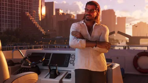 Arms crossed at the helm of a boat, the skyline and a raised drawbridge behind him at sunset.